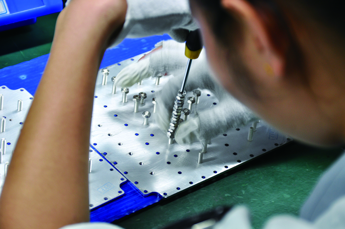 A technician tightening screws during assembly of a passive RF component.